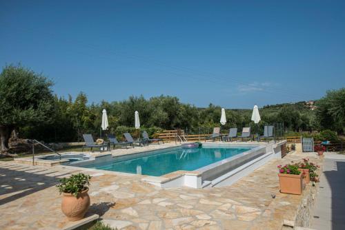 a swimming pool with chairs and umbrellas at Villa Martha Perithia Corfu in Perítheia