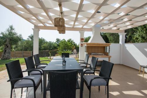 a patio with a table and chairs under a pergola at Villa Martha Perithia Corfu in Perítheia