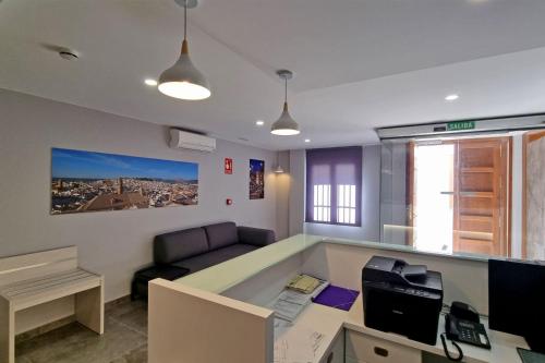 ein Büro mit einem Schreibtisch mit einem Computer und einem Sofa in der Unterkunft Apartamentos Antequera in Antequera