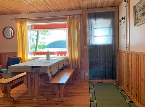 een eetkamer met een tafel en een raam bij Lappalaisen lomamökit Suviranta in Puumala