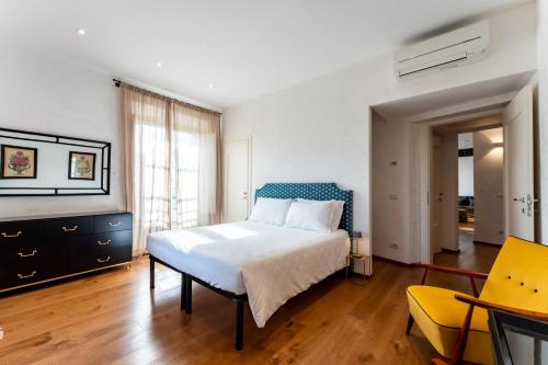 a bedroom with a white bed and a yellow chair at AT Home Santacroce in Florence