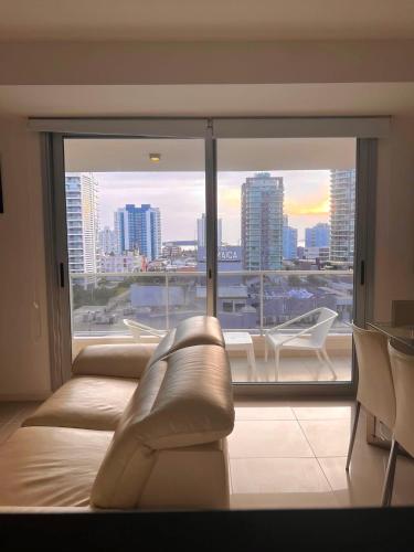 a living room with a couch and a large window at Apartamento dos dormitorios en Arenas del Mar in Punta del Este