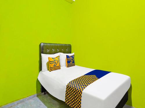 Habitación verde con cama con almohadas en SPOT ON 92786 Homestay Barokah, en Gresik