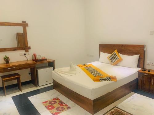 a bedroom with a bed with a wooden headboard and a desk at Hotel River Front in Tissamaharama