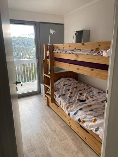 une chambre avec un lit superposé et une grande fenêtre dans l'établissement Appart 6 personnes, balcon plein sud, à Flaine