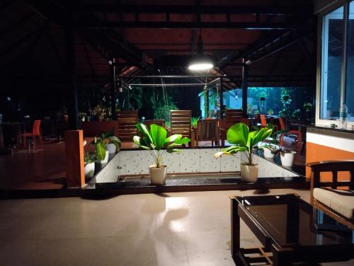 a restaurant with potted plants on a table in a room at Nature Valley Homestay Near Annapoorneshwari Temple in Kalasa