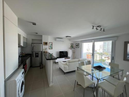 a living room with a glass table and a kitchen at Apartamento dos dormitorios en Arenas del Mar in Punta del Este