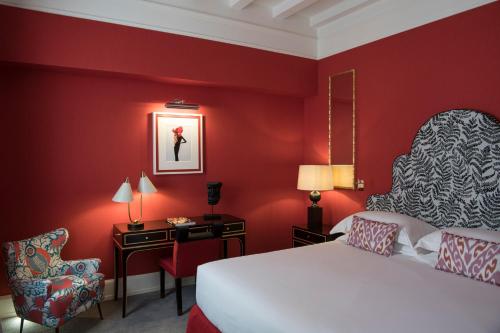 a bedroom with red walls and a bed and a chair at Maalot Roma - Small Luxury Hotels of the World in Rome
