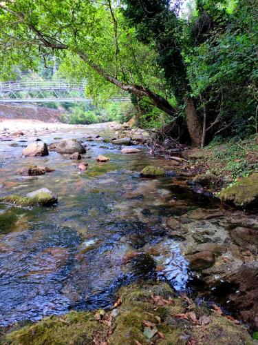 a river with rocks and trees and a bridge at The small waterfall house, la cascatella in Massa
