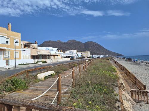 a beach with a fence and buildings and the ocean at Apartamentos La Calilla Cabo de Gata in El Cabo de Gata