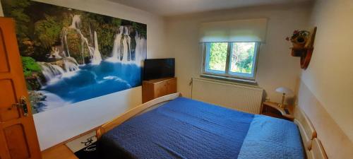 Un dormitorio con una cama azul con una pintura en la pared en Casă de vacanţă ,,La Vălucu", en Curtea de Argeş