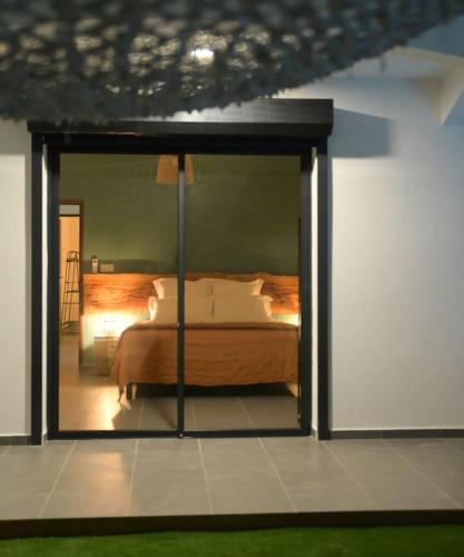 a bedroom with a bed and a large glass door at La Palmeraie Lodge Terrasse & Piscine et Jacuzzi in Matoury