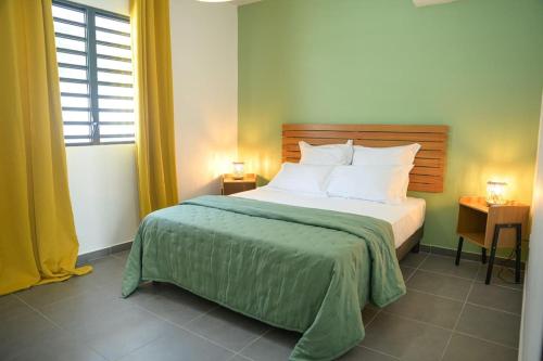 a bedroom with a large bed with a green blanket at La Palmeraie Lodge Terrasse & Piscine et Jacuzzi in Matoury