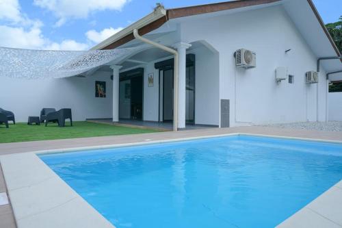 - une piscine en face d'une maison blanche dans l'établissement La Palmeraie Lodge Terrasse & Piscine et Jacuzzi, à Matoury