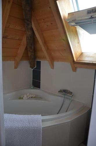 Cette chambre dispose d'une baignoire et d'un plafond en bois. dans l'établissement Corps de Ferme Labarthe à Pimbo, à Pimbo