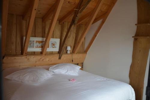 Una cama blanca en una habitación con techos de madera. en Maison de Ferme en Pimbo