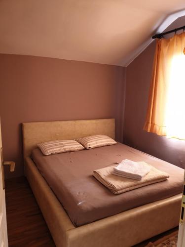 a bedroom with a bed with two pillows and a window at Vila Fantastico in Skopje
