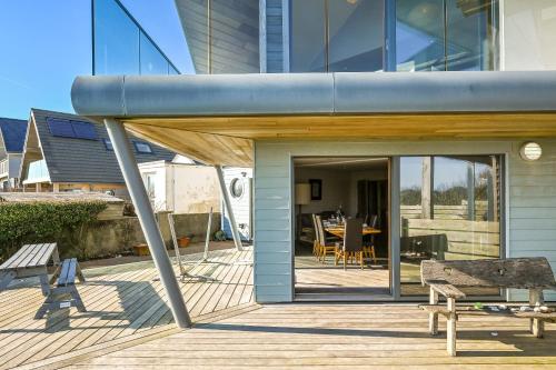 a house with a wooden deck with a bench at Le Var - Beachfront home in Bracklesham Bay in Chichester