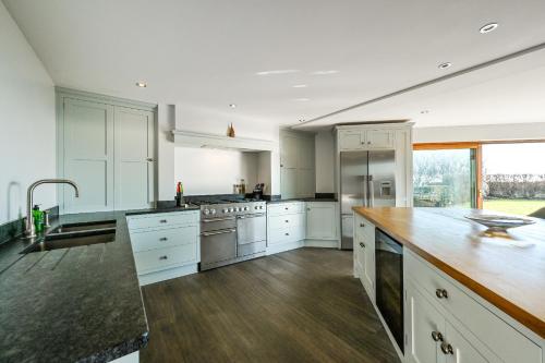 a large kitchen with white cabinets and a wooden counter top at Le Var - Beachfront home in Bracklesham Bay in Chichester