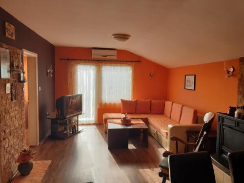 an orange living room with a couch and a tv at Vila Fantastico in Skopje