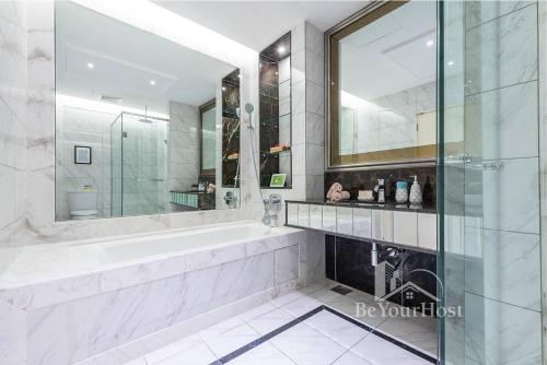 een witte badkamer met een bad en een spiegel bij Dorsett Residences Sri Hartamas (Kuala Lumpur) in Kuala Lumpur