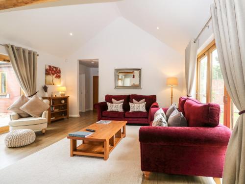 a living room with two red couches and a table at Squirrels Drey in Fareham