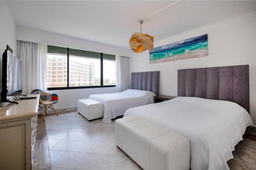 um quarto de hotel com duas camas e uma televisão de ecrã plano em State of the Art Condos en la mejor Playa de Cancun frente a PLAZA LA ISLA em Cancún