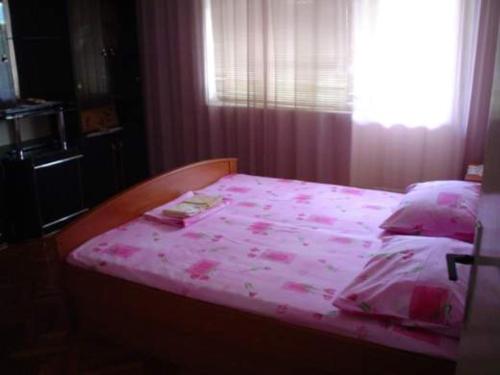 a bedroom with a pink bed with a window at Apartments Jerković in Stari Grad