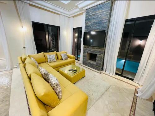 un sofá amarillo en la sala de estar con chimenea en The Villa avec piscine 4 chambres, en Marrakech