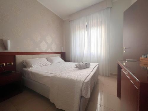 a bedroom with a bed with a white blanket and a window at Hotel Paradiso in Lago Patria