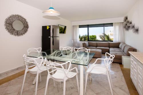 a kitchen and living room with a glass table and white chairs at State of the Art Condos en la mejor Playa de Cancun frente a PLAZA LA ISLA in Cancún