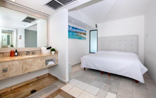 a bedroom with a bed and a sink and a mirror at State of the Art Condos en la mejor Playa de Cancun frente a PLAZA LA ISLA in Cancún