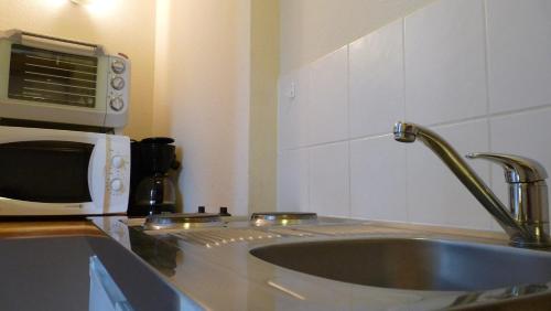 une cuisine avec un évier et un micro-ondes dans l'établissement Résidence Le Castel Médicis, à Le Mont-Dore