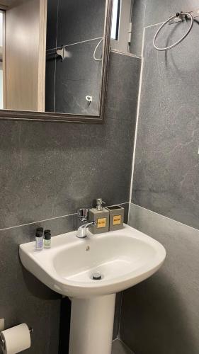 W łazience znajduje się biała umywalka i lustro. w obiekcie Emerald Suites w mieście Vryses