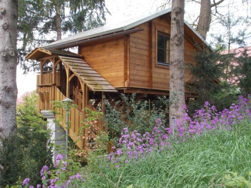 una casa del árbol en el bosque con flores púrpuras en Baumhaus Wolfshöhle, en Fischach