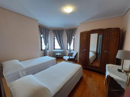 een hotelkamer met 2 bedden en een stoel bij Olympos Philoxenia, μεταξύ βουνού και θάλασσας in Kateríni