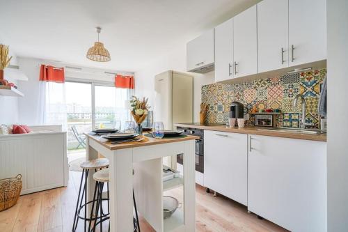 une cuisine avec des armoires blanches et une table avec des tabourets dans l'établissement diamant, à Choisy-le-Roi