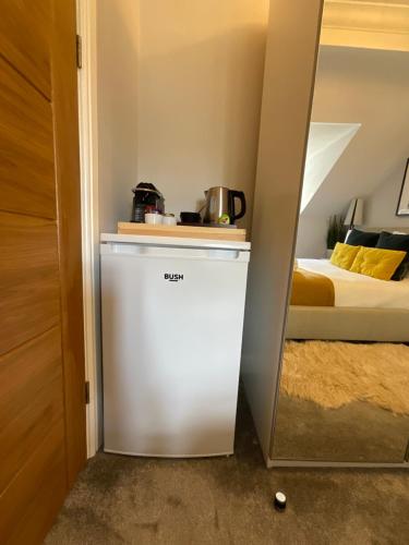 a small refrigerator in a room with a bed at Home away from home in London