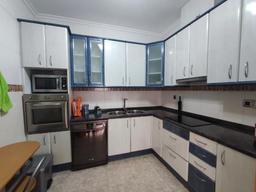 uma cozinha com armários brancos e electrodomésticos pretos em Piso céntrico reformado de excelente ubicación em Vinarós