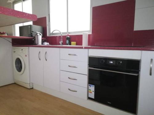 バレンシアにあるMalvarrosa Beachの白いキャビネットと黒い食器洗い機付きのキッチンが備わります。