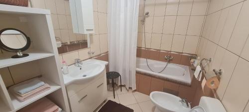 a bathroom with a sink and a toilet and a tub at Apartman Neli in Delnice