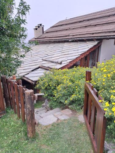 uma casa velha atrás de uma cerca com flores amarelas em Baita LE SERE em Sestriere