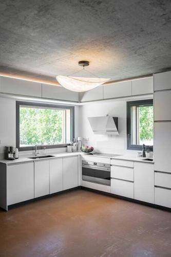 une cuisine avec des placards blancs et une grande fenêtre dans l'établissement Chalet Zenspace, au Grand-Bornand