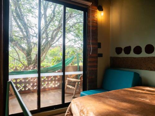 um quarto com uma cama e uma porta de vidro deslizante em La Casita del Bosque, Minicasa totalmente equipada, con tina y agua caliente em Barichara