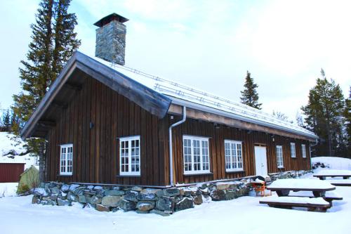 a log cabin in the snow with a picnic table at Grindastugu cabin right by Liatoppen Ski Centre. in Al