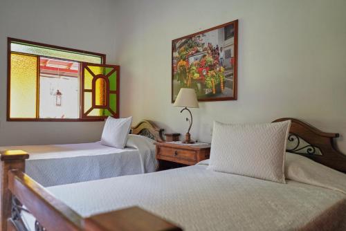 a bedroom with two beds and a table and a window at FINCA EL PATRIARCA in Armenia