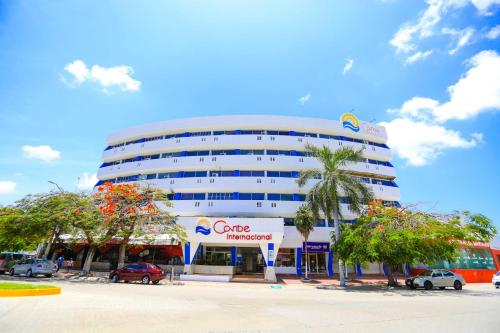 a large white building with a palm tree in front of it at Hotel Caribe Internacional Cancun in Cancún