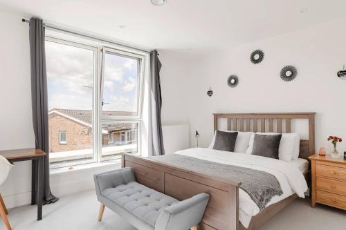 een slaapkamer met een bed, een stoel en ramen bij A Modern Lavish En-suite Bedroom in Londen