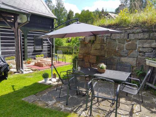a table and chairs with an umbrella in a yard at Medová chaloupka Jetřichovice České Švýcarsko in Jetřichovice