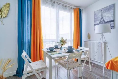une salle à manger avec une table et des chaises blanches dans l'établissement Saphir T2 proche Paris, à Vitry-sur-Seine
